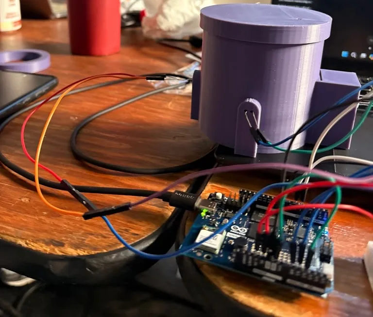 Side view: the photoresistor holder at 90° to the beam facing the camera, its two leads coming out through the fin, the LED box on the right, and the Arduino UNO Q on a USB-C cable in front